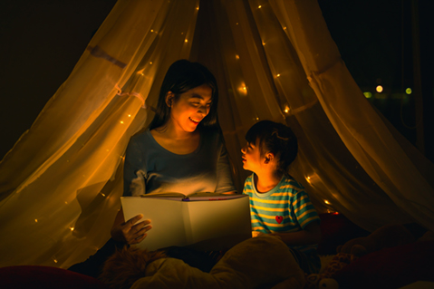 Mom and child reading in dimly lit tent